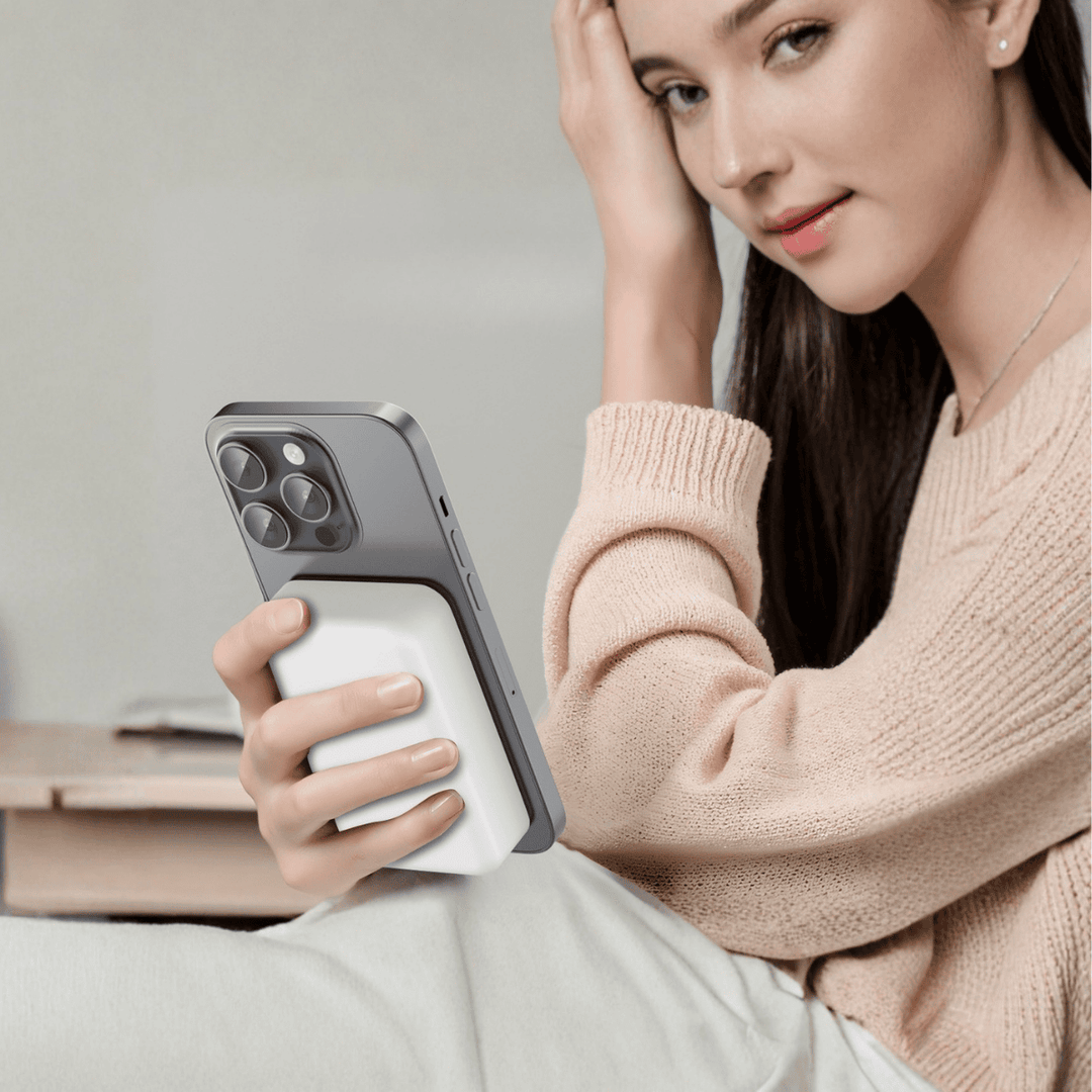 Woman holding an iPhone with a white magnetic wireless power bank attached