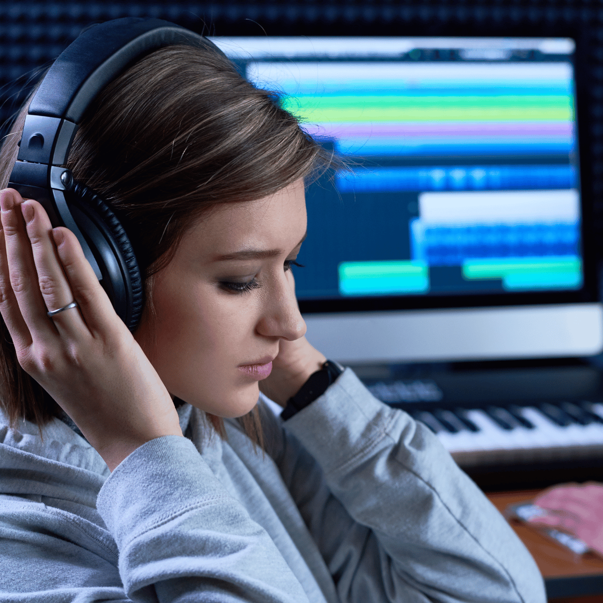 Woman in over-ear headphones listening at a music production desk