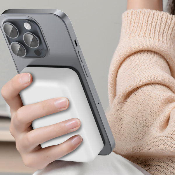 Hand holding an iPhone with a white magnetic power bank attached, close-up
